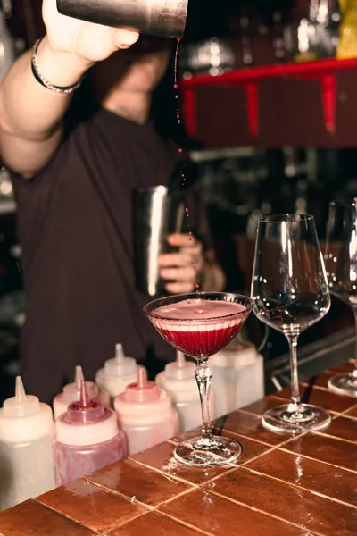 A bartender pouring a red cocktail behind the bar at Čin Čin, Vračar