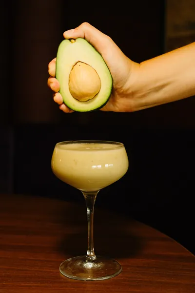 An avocado being squeezed over a fresh cocktail at Čin Čin bar