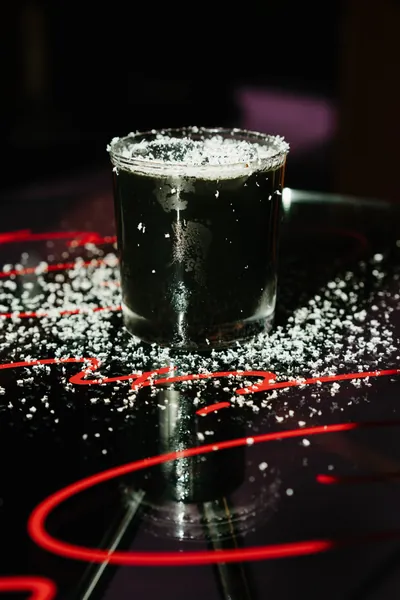 A dark cocktail with a salted rim on a red-neon table at Čin Čin, Belgrade